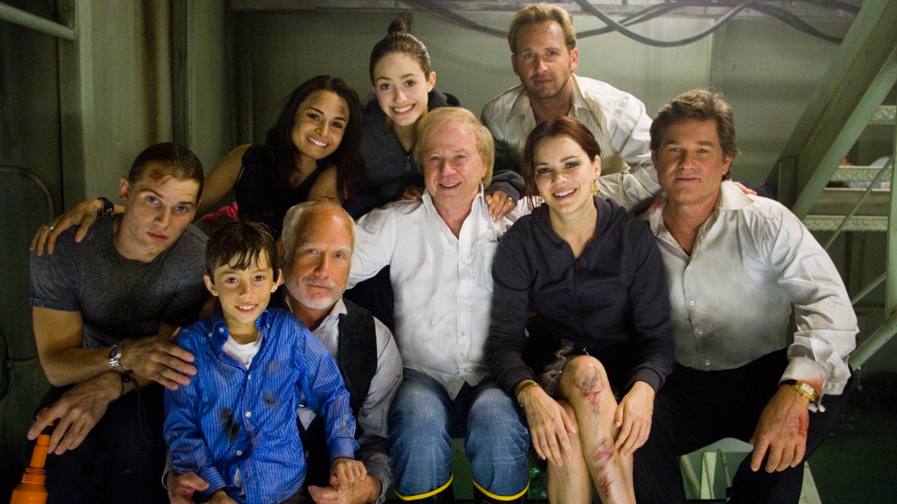 O diretor Wolfgang Petersen no meio, de camisa social branca, rodeado pelo elenco de Poseidon.