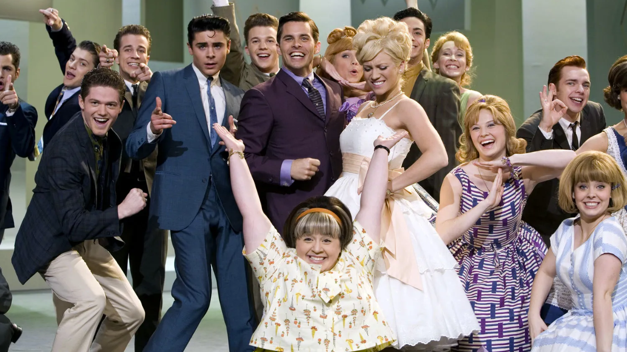 James Marsden como Corny Collins de terno roxo; ao seu redor, em sentido horário, estão Brittany Snow como Amber, Nikki Blonsky como Tracy e Zac Efron como Link.