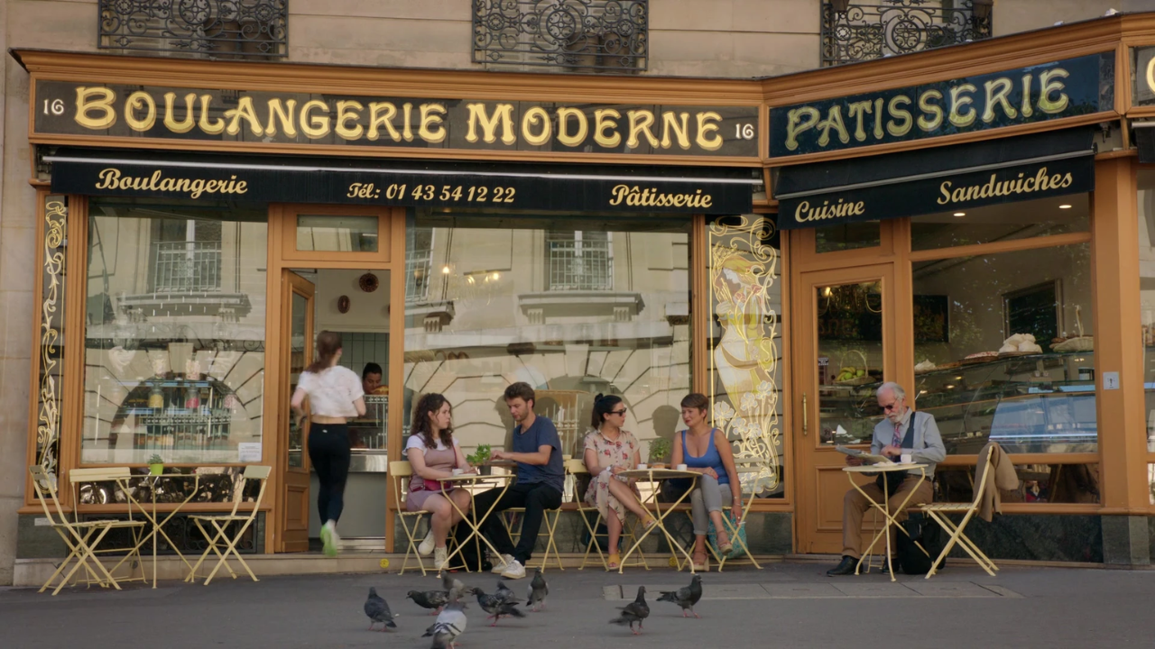 Emily (Lily Collins) entrando na Boulangerie Moderne em cena de Emily em Paris.